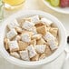 A bowl of Bite Size Frosted Shredded Wheat cereal with milk and fruit on a white plate.