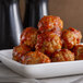 A close up of Spring Glen Fresh Foods meatballs in marinara sauce on a white plate.