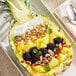 A Gold Pineapple with fruit salad inside.