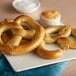 Two J & J Cheddar Cheese Stuffed Soft Pretzels on a plate with dipping sauce.