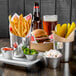 A silver round sauce cup with ketchup on a tray of food on a table.