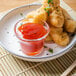 A plate of fried food with La Choy sweet and sour sauce.