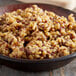 A bowl of brown rice with raisins on a table.