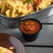 A bowl of nachos next to a bowl of Rosarita medium green chile salsa.