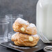 A plate with two pastries and a fork with powdered sugar on top.