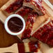 A cutting board with ribs and barbecue sauce.