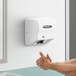 A man using a white American Dryer hand dryer to dry his hands.