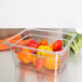 A Carlisle clear polycarbonate food pan filled with broccoli on a counter.