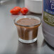 A bottle of Ken's Foods Balsamic Vinaigrette on a counter next to a small glass of brown liquid.