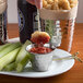 A plate of food with a dipping sauce in a Choice stainless steel round sauce cup.