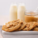 David's Cookies preformed peanut butter cookies on a white plate with a glass of milk.