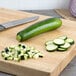 A medium green squash on a cutting board with a knife.