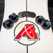 An Atomic air hockey table with black circular objects and a red arrow.