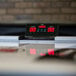 An Atomic air hockey table with a digital scoreboard on a counter.