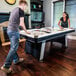 A man and woman playing air hockey on an Atomic game table.