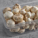 A plastic container of white mushrooms.