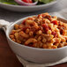A bowl of macaroni with beef and vegetables in sauce.
