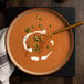 A bowl of soup with roasted unsalted pumpkin seeds on a table.