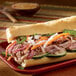 A sandwich with chicken and vegetables on a Rich's French baguette on a plate.