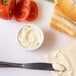 A knife spreading Ken's Extra Heavy Mayonnaise on a piece of bread.