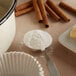 A spoonful of Clabber Girl baking powder next to a bowl of flour.