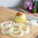 Sliced Spanish onions on a cutting board with a knife.