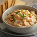 A bowl of Blount Fine Foods Shrimp and Roasted Corn Chowder with bread on the side.