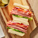 A sandwich with Kunzler smoked turkey ham, lettuce, and tomato on a cutting board.