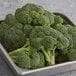 A metal container filled with iceless broccoli crowns on a counter.