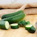 A cucumbers and slices on a wooden surface with a knife.