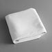 A folded white Intedge tablecloth on a gray surface.