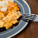 A Fineline black plastic plate with gold bands holding a plate of pasta with a fork.