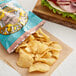 A bag of Dirty Potato Chips Maui Onion next to a sandwich on a table.