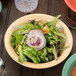 A bowl of squash salad with carrots and onions in a yellow Diamond Harvest melamine bowl on a table.