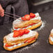 An unfilled eclair pastry shell with strawberries on top.