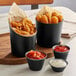 Three matte black stainless steel round sauce cups with fries and dipping sauces.