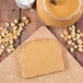 A piece of bread with Skippy Creamy Peanut Butter spread on it sitting next to a jar of Skippy Creamy Peanut Butter.