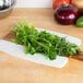 A bunch of green cilantro leaves on a cutting board.