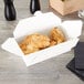 A white Fold-Pak Bio-Pak take-out box filled with fried chicken.