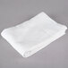 A folded white Oxford bath towel on a gray surface.