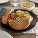 A plate with two Father Sam's Bakery whole wheat pita pockets with vegetables and cheese on a table.