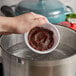 A hand pouring Minor's Chipotle Flavor Concentrate into a pot.