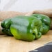 A close-up of three large green bell peppers on a cutting board.