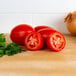 A group of plum tomatoes and parsley on a table.