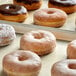 A tray of Pillsbury Elite Raised Donuts with a chocolate covered donut.