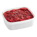 A white bowl filled with sliced strawberries in a red sauce.
