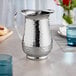 An Acopa stainless steel pitcher on a table.