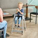 A gray assembled high chair designed for children, shown in use at a restaurant table.
