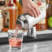 A person using an Acopa stainless steel cobbler cocktail shaker to pour a drink.