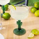 A Libbey Cactus Margarita Glass on a table with a drink and lime wedge